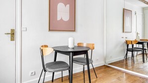 A room with a round table, two chairs, a white vase, and a framed picture on the wall. - Blueground | St Paul, nr Bastille & Le Marais (Paris)