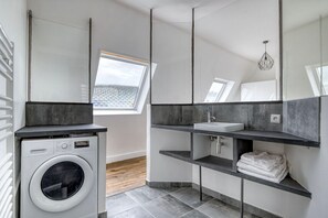 Ein modernes Badezimmer mit Waschmaschine, Waschbecken und einem Fenster mit Blick auf die Stadt.