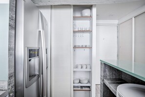 Kitchen features a refrigerator, pantry, and sink on a marble countertop.