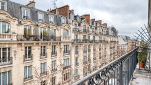 Uma fileira de edifícios parisienses clássicos com varandas ornamentadas e grade de ferro forjado.