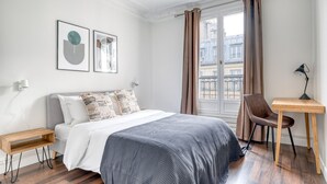 Um quarto moderno com cama, mesas de cabeceira, escrivaninha e uma cadeira.