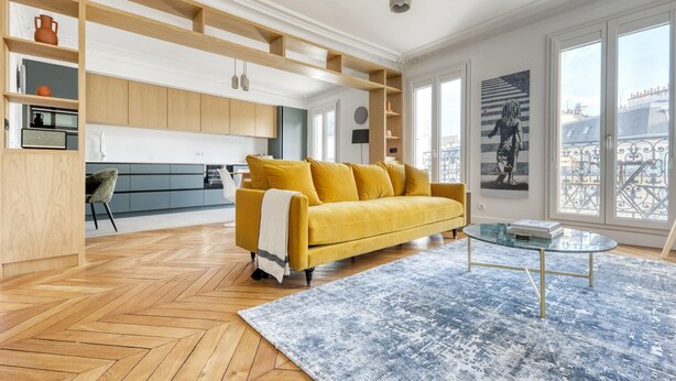 A modern living room with a yellow sofa, a glass coffee table, and a herringbone wooden floor. - Blueground | Rochechouart, furnished, balcony (Paris)