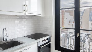 A modern kitchen with white cabinets, a stainless steel sink, and an oven. - Blueground | Bourse Sentier/Les Halles, nr Louvre (Paris)