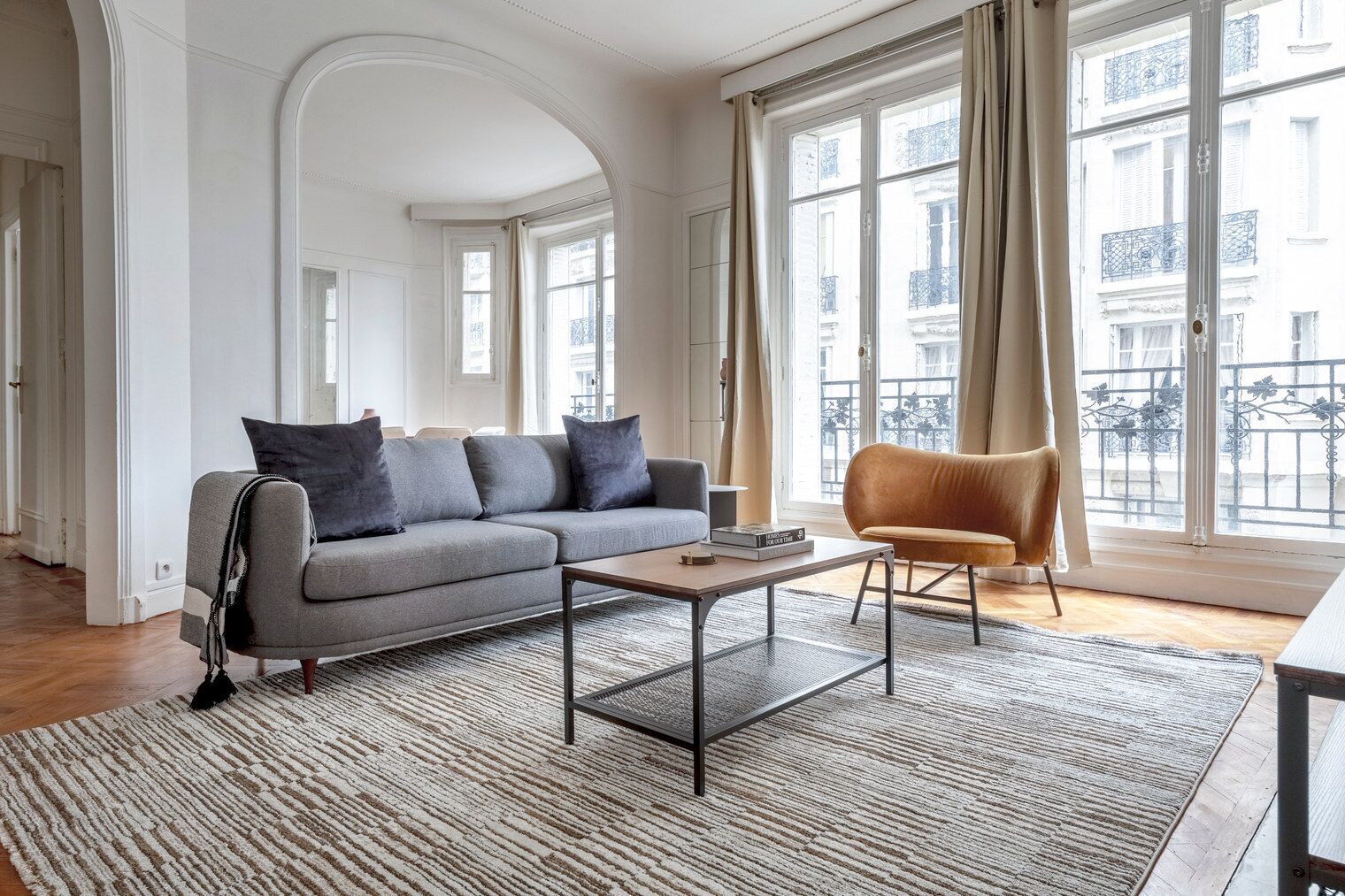 A modern living room with a grey sofa, a wooden coffee table, and a brown armchair.