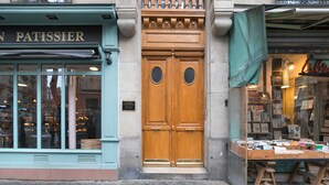 A storefront with a wooden double door and a display of books outside. - Blueground | Lamark-Caulaincourt, elevator (Paris)