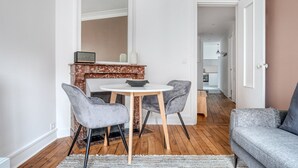 A dining area with a round table and two chairs, a fireplace, and a sofa in a modern apartment. - Blueground | Lamark-Caulaincourt, elevator (Paris)