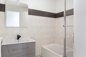 Bathroom features a white sink, large mirror, and a bathtub with a glass shower enclosure.