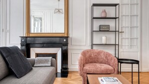 Ein Wohnzimmer mit Kamin, einer Couch, einem Sessel, einem Couchtisch und einem Bücherregal.