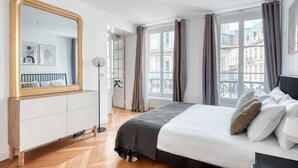 Ein modernes Schlafzimmer mit einem großen Bett, einer Stehlampe, einem Schminktisch und einem großen Spiegel.