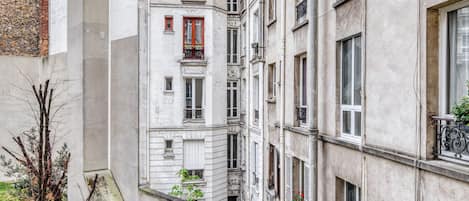 A narrow alleyway between buildings with a small garden area.