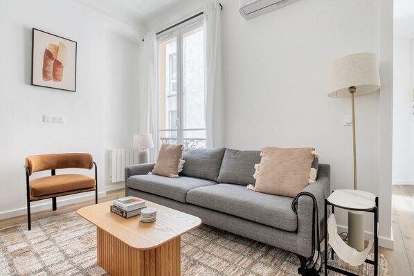 A modern living room with a grey sofa, a brown chair, a wooden coffee table, and a floor lamp.