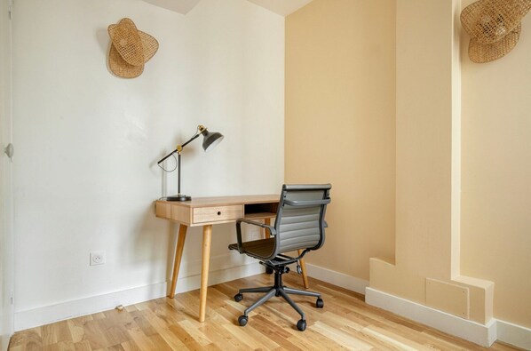 A workspace with a desk, chair, lamp, and two wall-mounted baskets.