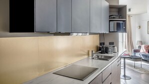 A modern kitchen with grey cabinets, a stainless steel sink, and a built-in microwave. - Blueground | Canal Saint Martin, near shops (Paris)