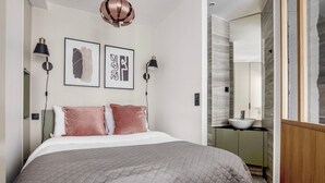 A modern bedroom with a large bed, two wall-mounted lamps, and a large mirror. - Blueground | Canal Saint Martin, near shops (Paris)