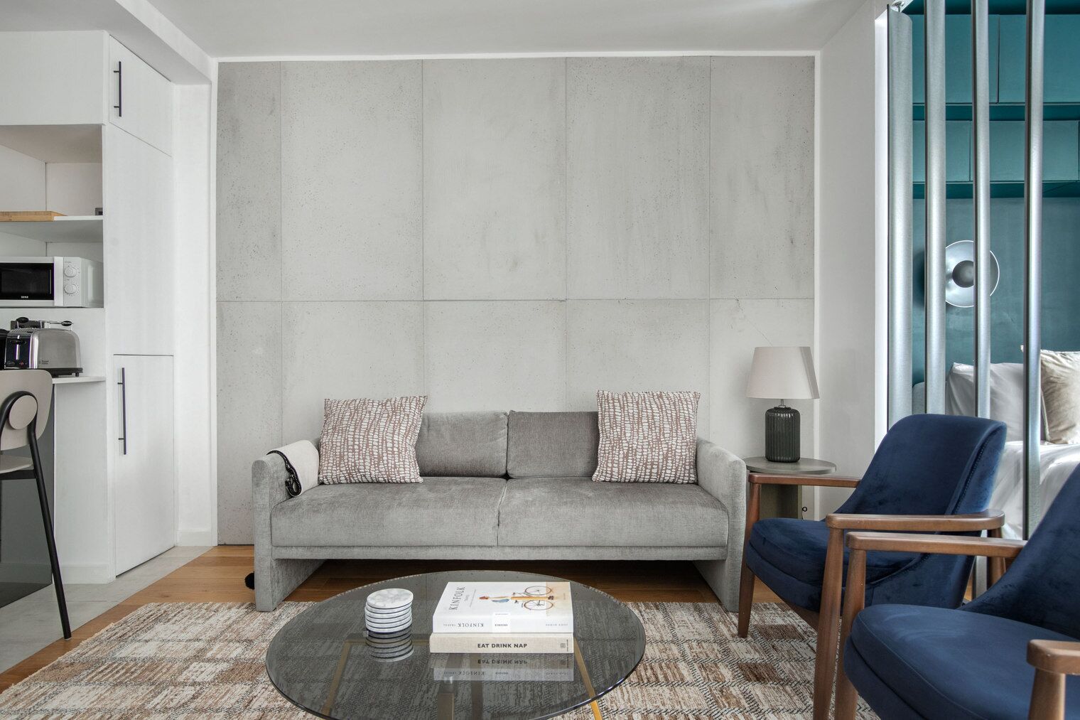 A modern living room with a grey sofa, a coffee table, and a blue armchair.