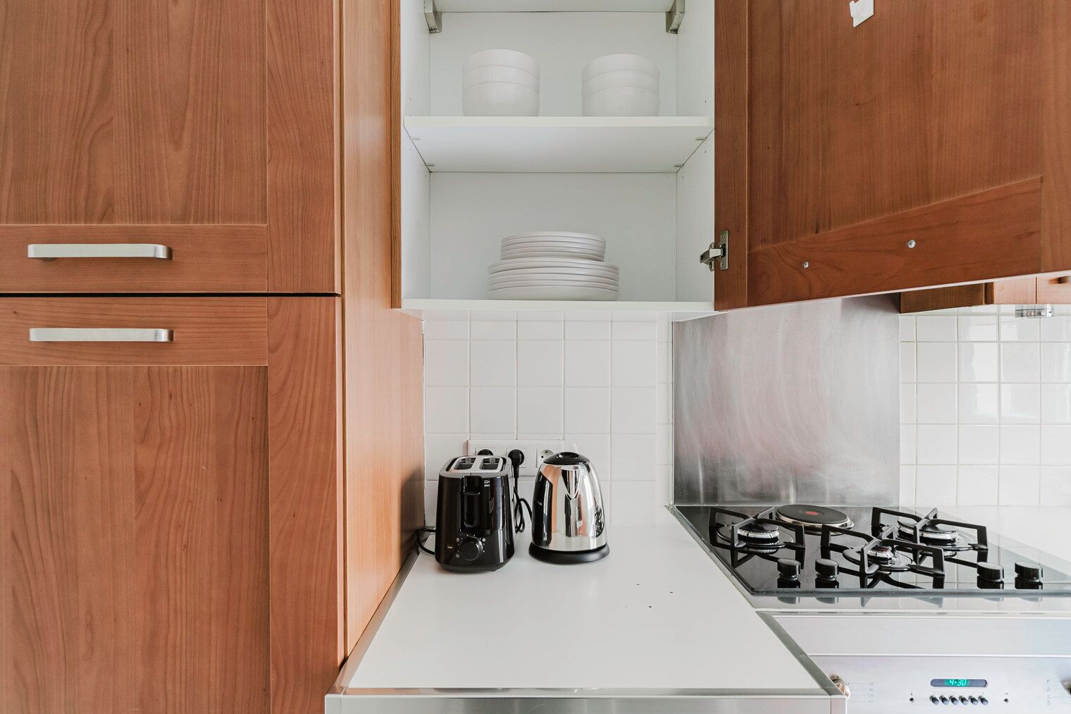 A kitchen with wooden cabinets, a white countertop, a gas stove, and a toaster.