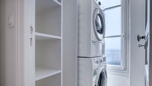 A laundry room with two front-loading washing machines and a window. - Blueground | Saint Georges, nr Palais Garnier (Paris)