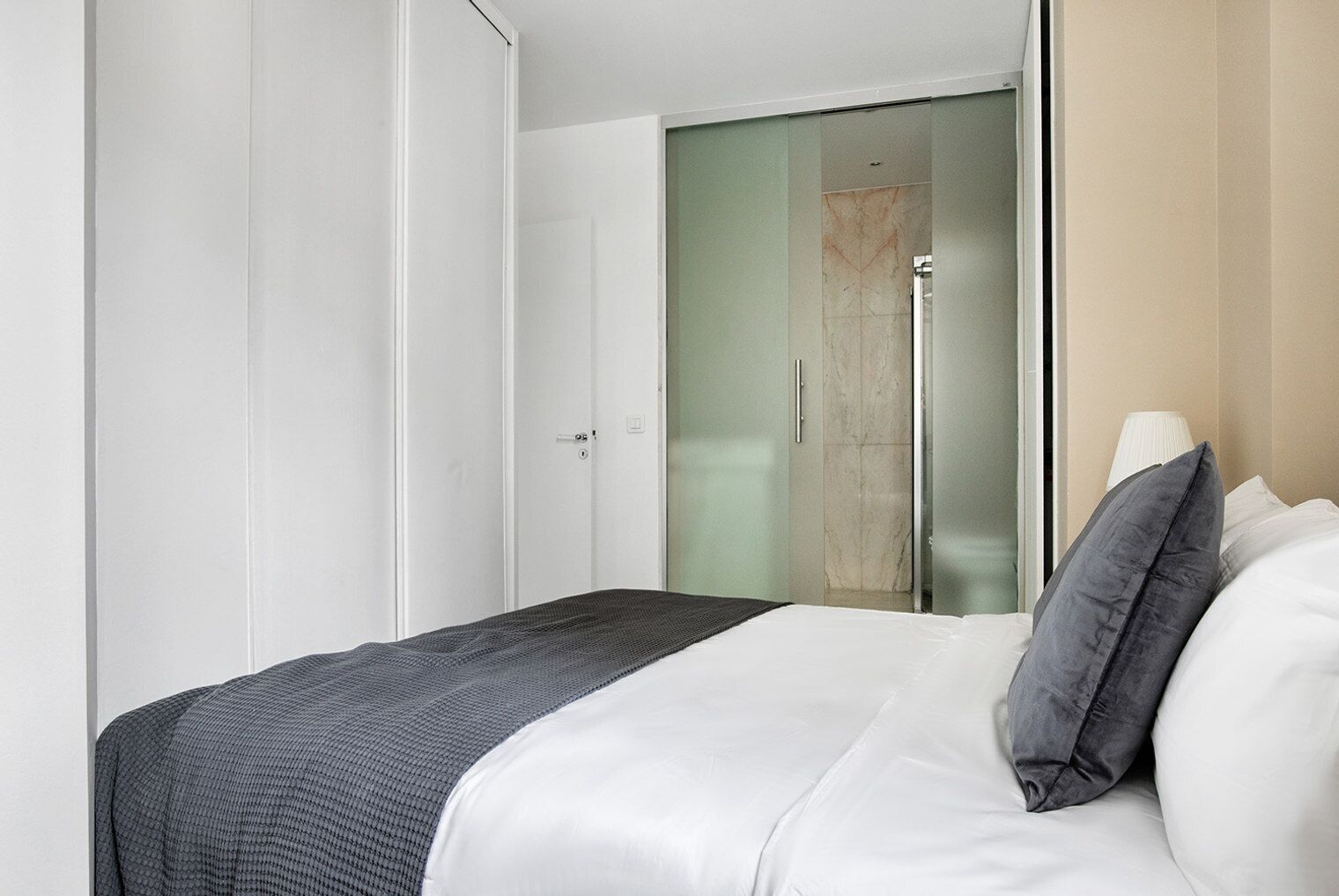 A modern hotel room with a bed, a wardrobe, and a shower area.