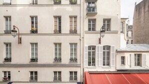 A multi-story building with balconies, large windows, and a red awning. - Blueground | Saint-Honoré, nr opera (Paris)