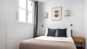 A bedroom with a bed, bedside tables, a window, and wall-mounted lamps. - Blueground | Saint-Honoré, nr opera (Paris)