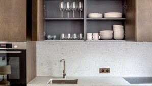 A modern kitchen with a built-in oven, a stainless steel sink, and a marble countertop. - Blueground | Saint-Honoré, nr opera (Paris)