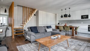 Ein modernes Wohnzimmer mit einem grauen Sofa, einem Holztisch und einer Treppe mit Holzgeländern.