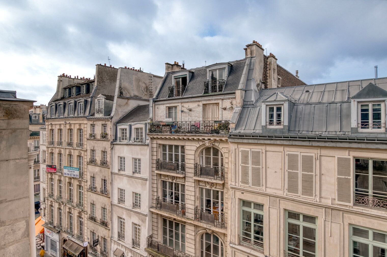A row of historic European buildings with multiple stories, balconies, and classic architectural details.