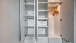 Ein begehbarer Kleiderschrank mit offenen Regalen, Kleiderstangen und Schubladen.