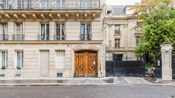 A historic building with a large wooden double door, a balcony with wrought iron railings, and a gated entrance. - Blueground | Pigalle, washer, nr festive area (Paris)