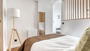 Une chambre à coucher moderne avec un grand lit, une lampe sur pied et un miroir.
