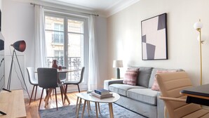 Un salon moderne comprenant un canapé, une table à manger avec des chaises, une table basse et un lampadaire.