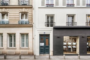 Traditional architecture meets charming entrance with a dark green door and decorative ironwork.