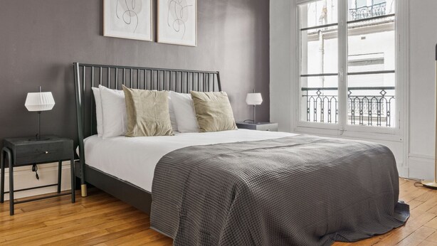 A bedroom with a bed, two bedside tables, a window with a view, and two framed artworks on the wall. - Blueground | Trocadero, courtyard, nr museums (Paris)