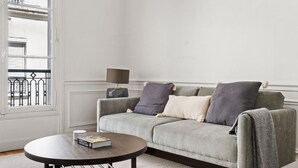 A living room with a grey sofa, a round coffee table, and a lamp. - Blueground | Trocadero, courtyard, nr museums (Paris)