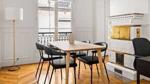 A dining area with a wooden table and black chairs, a floor lamp, and a decorative fireplace with a gold accent. - Blueground | Trocadero, courtyard, nr museums (Paris)