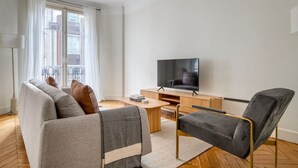A modern living room with a sofa, a chair, a coffee table, and a flat-screen TV. - Blueground | Vaugirard, lively area (Paris)