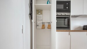A kitchen with white cabinets, a microwave, and an oven. There are three hanging kitchen towels. - Blueground | Victor Hugo, nr Trocadero Garden (Paris)