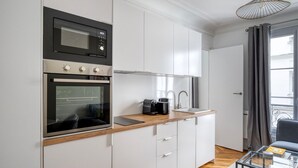 A modern kitchen with a built-in oven, a coffee maker, and a sink. - Blueground | Victor Hugo, nr Trocadero Garden (Paris)