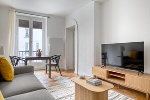 A modern living room with a sofa, TV, coffee table, and a dining area with a table and chairs.