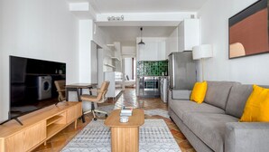 A modern living room with a grey sofa, wooden coffee table, and a TV on a wooden stand. - Blueground | Canal St Martin, near cafes & shops (Paris)