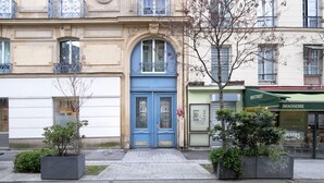 A building with a blue door, a bistro, and a restaurant. - Blueground | Canal St Martin, near cafes & shops (Paris)