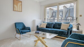 Un salon moderne avec un canapé bleu, un fauteuil bleu et une table basse en verre.