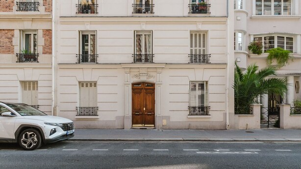 A white SUV parked in front of a building with a large wooden door and multiple windows with shutters. - Blueground | Commerce, close to offices & shops (Paris)