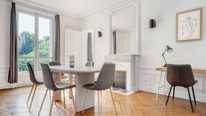 A dining area with a round table, four chairs, a fireplace, and a large mirror.