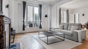 A spacious living room with a grey sofa, a black coffee table, and a fireplace.