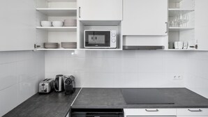 Eine moderne Küche mit weißen Schränken, einer Mikrowelle, einem Toaster und einem Wasserkocher.