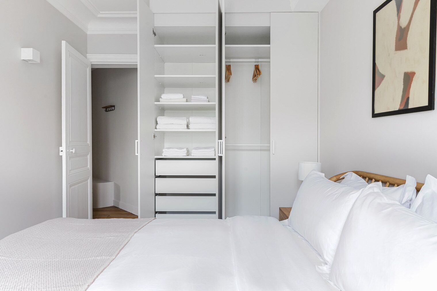 A bedroom with a bed, a wardrobe, and a nightstand.