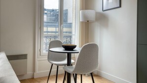 Un petit coin repas avec une table ronde et deux chaises, un bol posé sur la table et une lampe à côté.