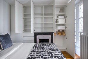 Un dormitorio con cama, chimenea, armario empotrado y ventana.