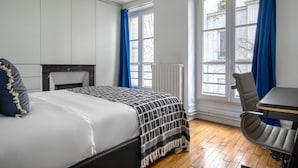 Ein Schlafzimmer mit einem Bett, einem Schreibtisch und zwei Fenstern mit Vorhängen.